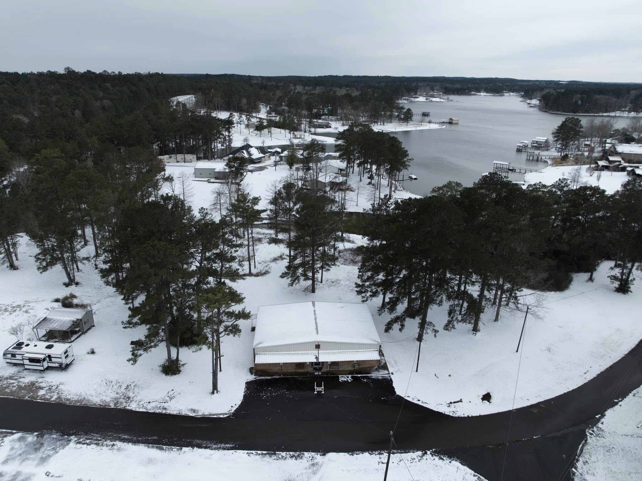 A snowy road with trees and a bridge in the background.